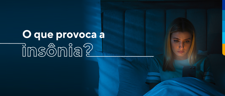 Texto: O que provoca a insônia?
Ao lado, mulher sentada na cama olhando o celular.