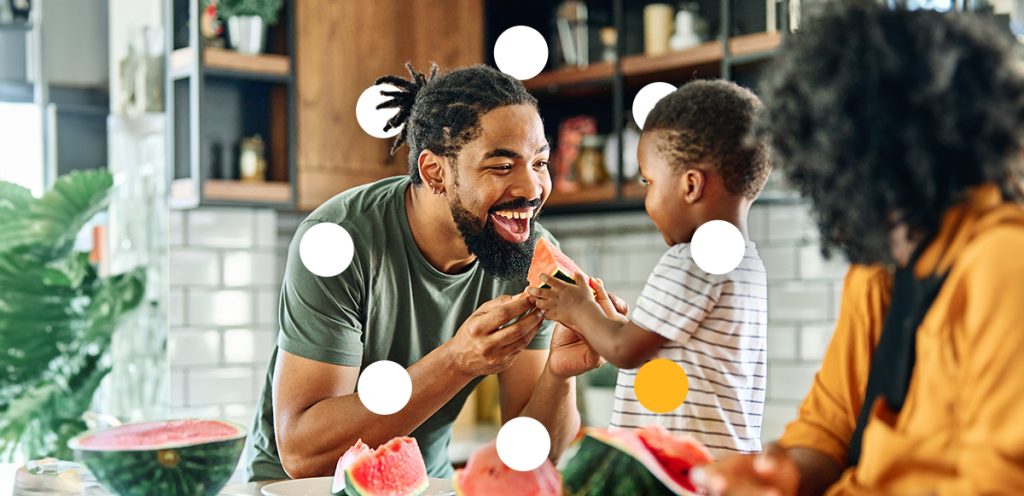 Imagem de um casal e uma criança segurando um pedaço de melancia, simbolizando Alimentação saudável para prevenção de doenças crônicas